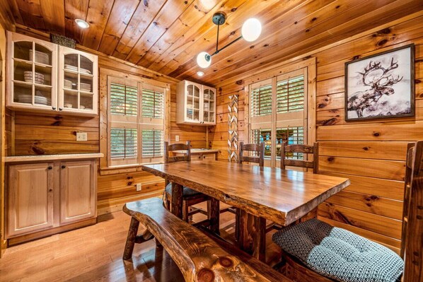 A wooden interior with a dining table, benches, and cabinets.