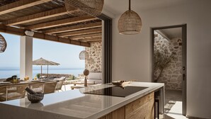 Een moderne keuken met een groot eiland, stenen muren en uitzicht op zee.