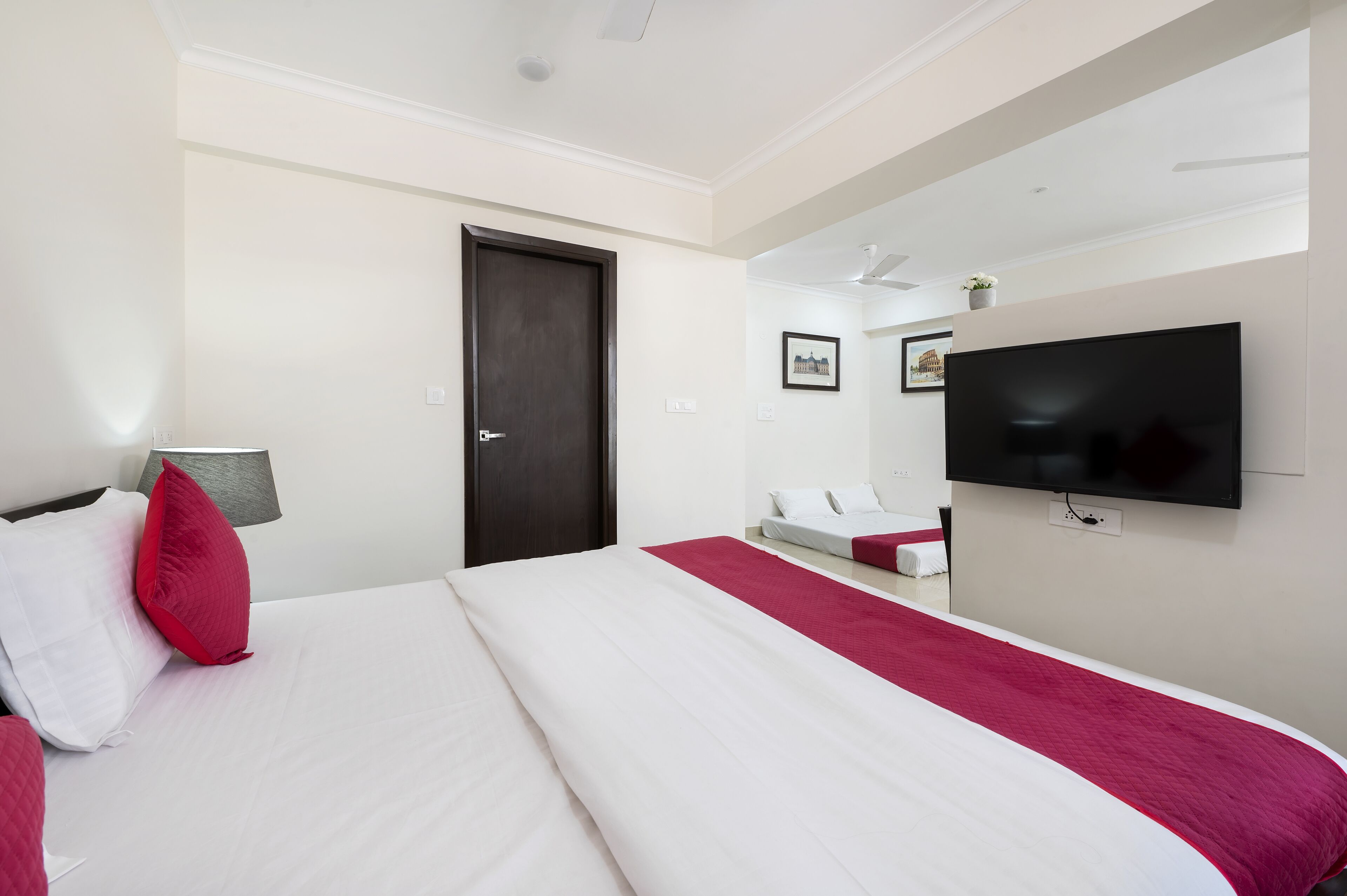 Een hotelkamer met een groot bed, een aan de muur bevestigde televisie en een deur.