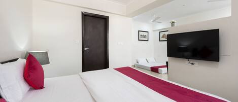 Una habitación de hotel con una cama grande, un televisor montado en la pared y una puerta.