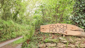 A wooden sign with the words "COACH HOUSE" in a forested area. - The Coach House at Thorn Farm (Exeter)