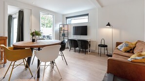 A modern living room with a dining area, a sofa, a TV, and a floor lamp.