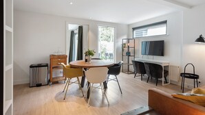 A modern living room with a round dining table, a sofa, a TV, and a radiator.