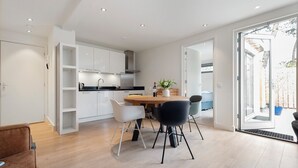 A modern kitchen with white cabinets, a wooden dining table, and black chairs.