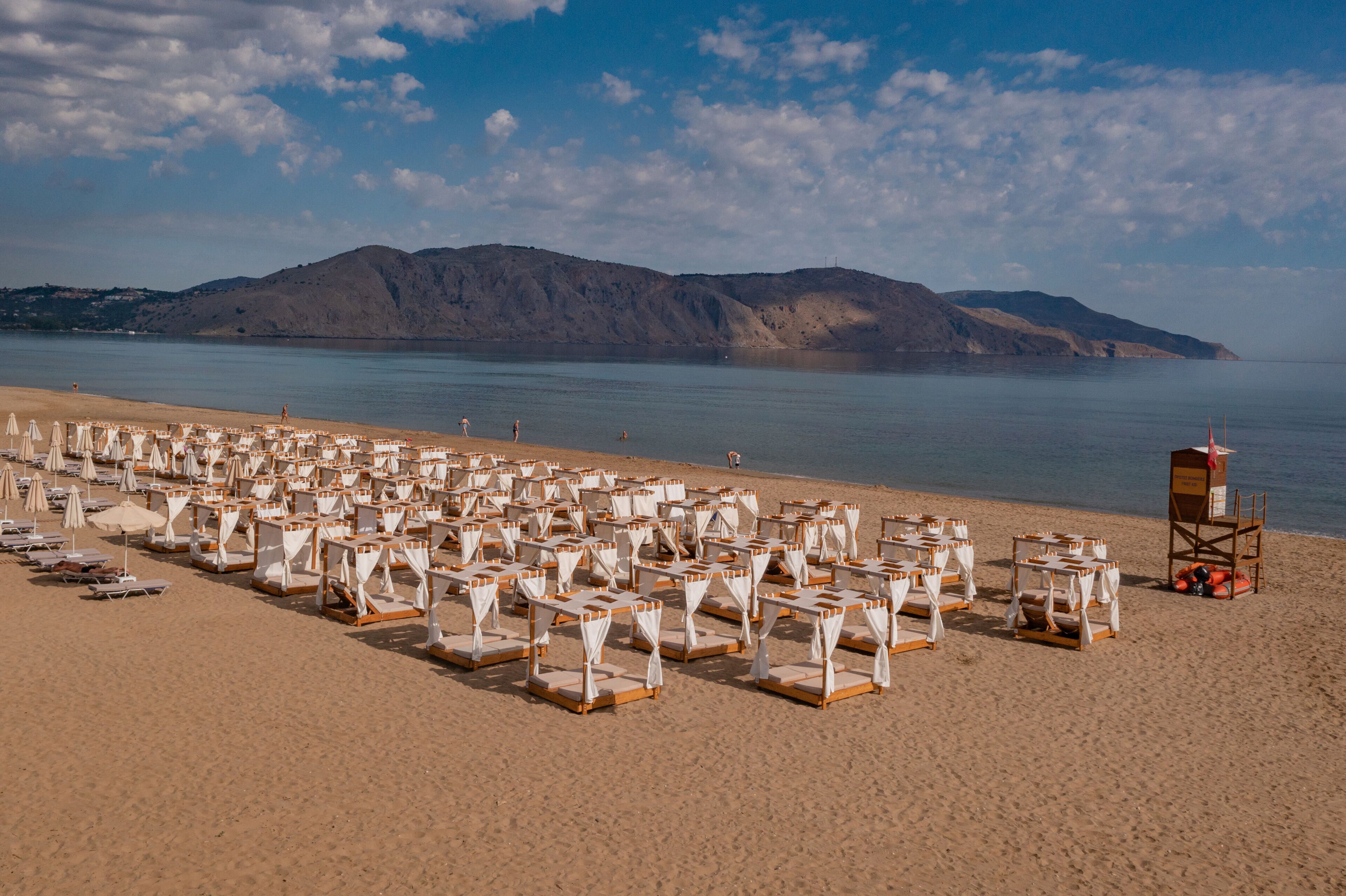 A beach with rows of sunbeds and a lifeguard tower.