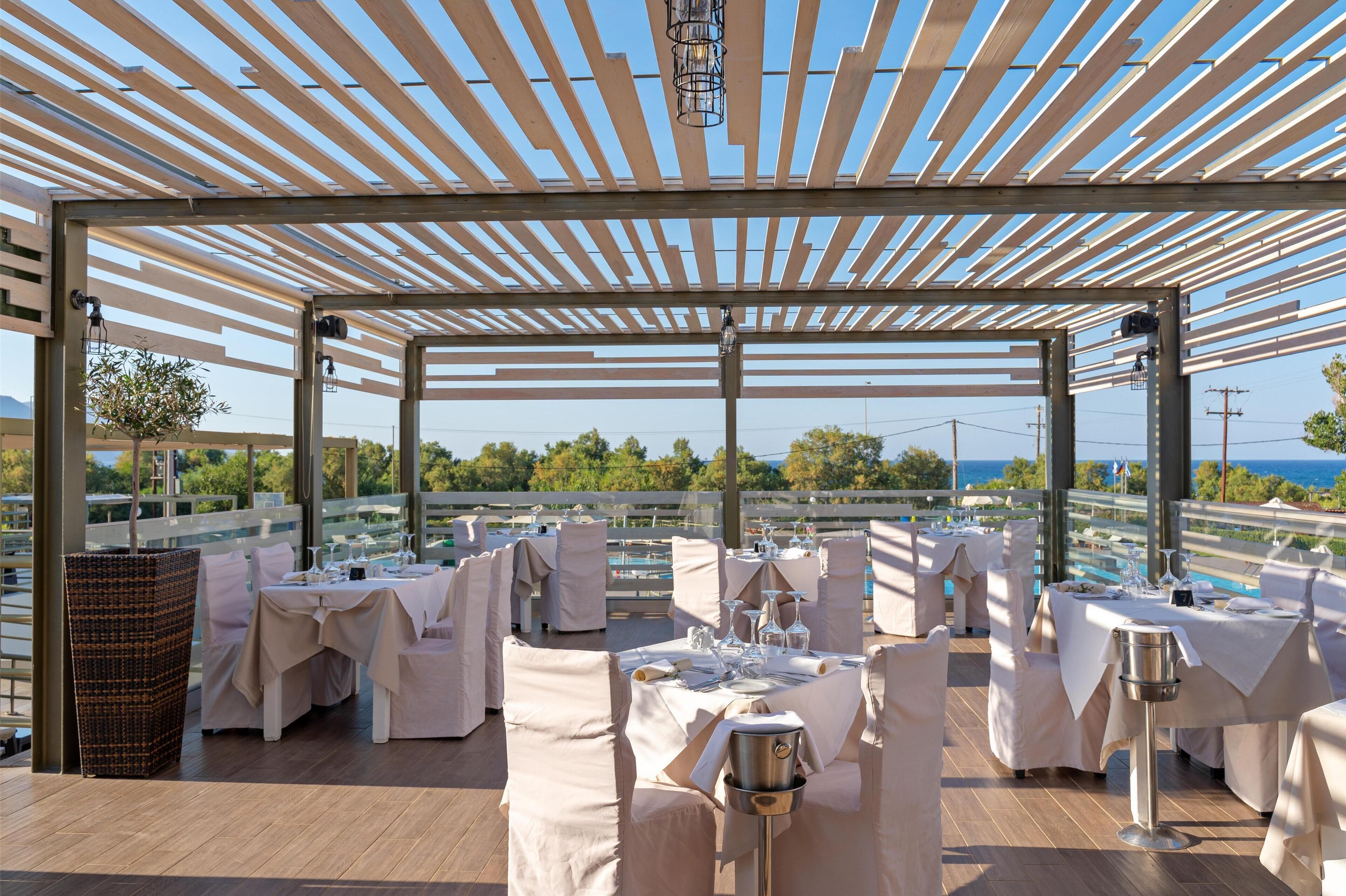 An outdoor dining area with tables set for a meal, overlooking a scenic view.