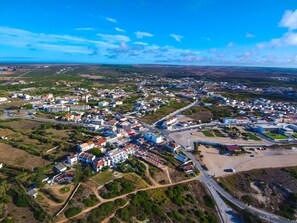 An aerial view of a town with a mix of residential and commercial buildings, roads, and green spaces. - Apartment Júlio Pomar (Sagres)