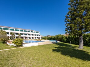 A hotel with a swimming pool, green lawns, and a large tree. - Apartment Júlio Pomar (Sagres)