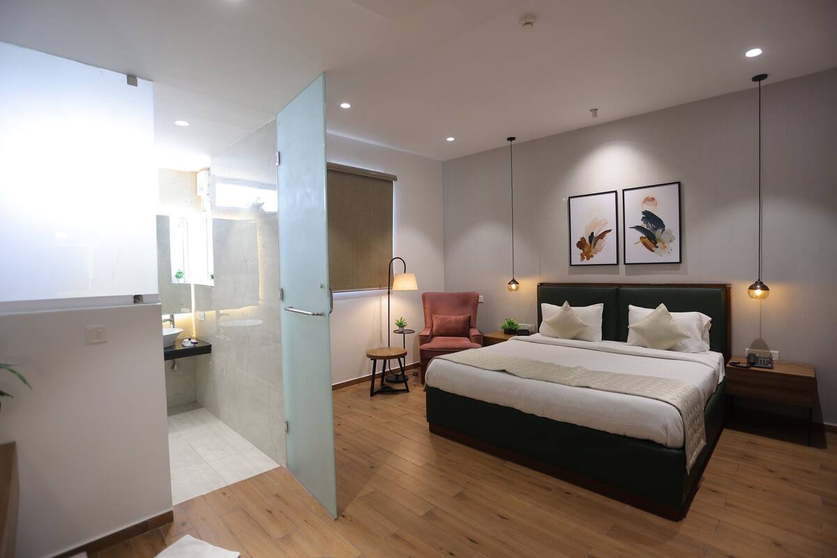 A modern bedroom with a large bed, bedside tables, a chair, and artwork on the wall.