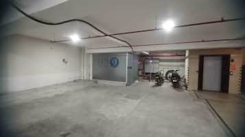 A parking garage with concrete floors and walls, a blue sign with the number 9, and a motorcycle parked near an elevator.