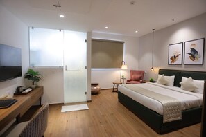 Une chambre d’hôtel moderne équipée d’un lit, d’un bureau, d’une chaise, d’une télévision et d’œuvres d’art.