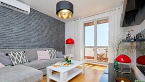 A modern living room with a grey sofa, white coffee table, and red pendant lights. - Vista Del Mare (Dubrovnik)