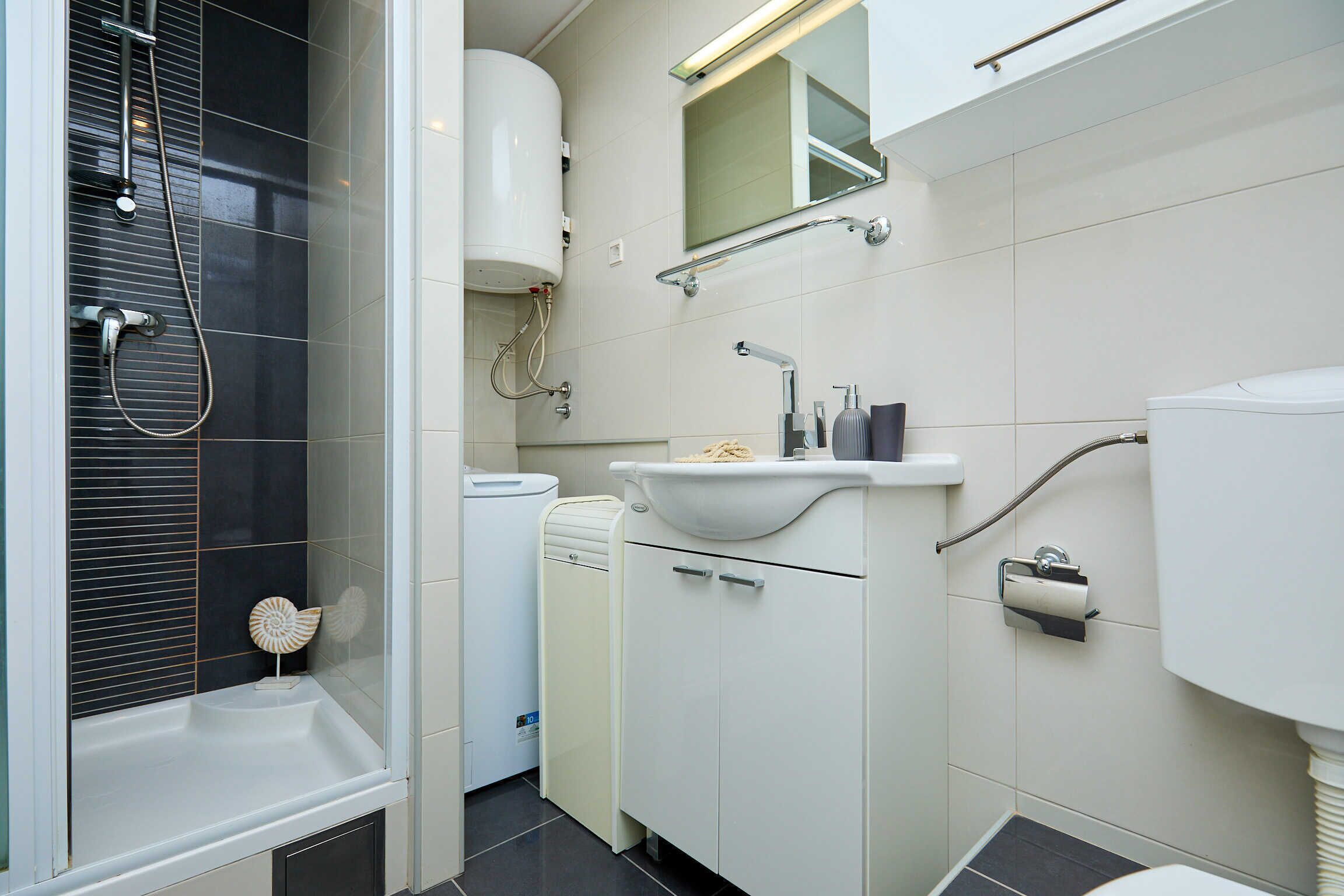 A modern bathroom with a shower, toilet, sink, and a mirror above the sink.
