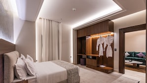 Una habitación de hotel moderna con una cama grande, un armario de madera, una zona de estar con un sofá verde y una pequeña mesa.