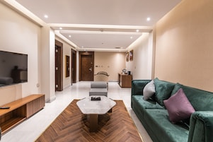 A modern living room with a sofa, a coffee table, a TV, and a herringbone-patterned floor.