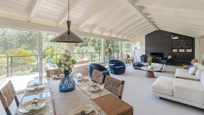 Un vaste espace de vie comprenant une table à manger pour quatre personnes, un canapé et une cheminée.