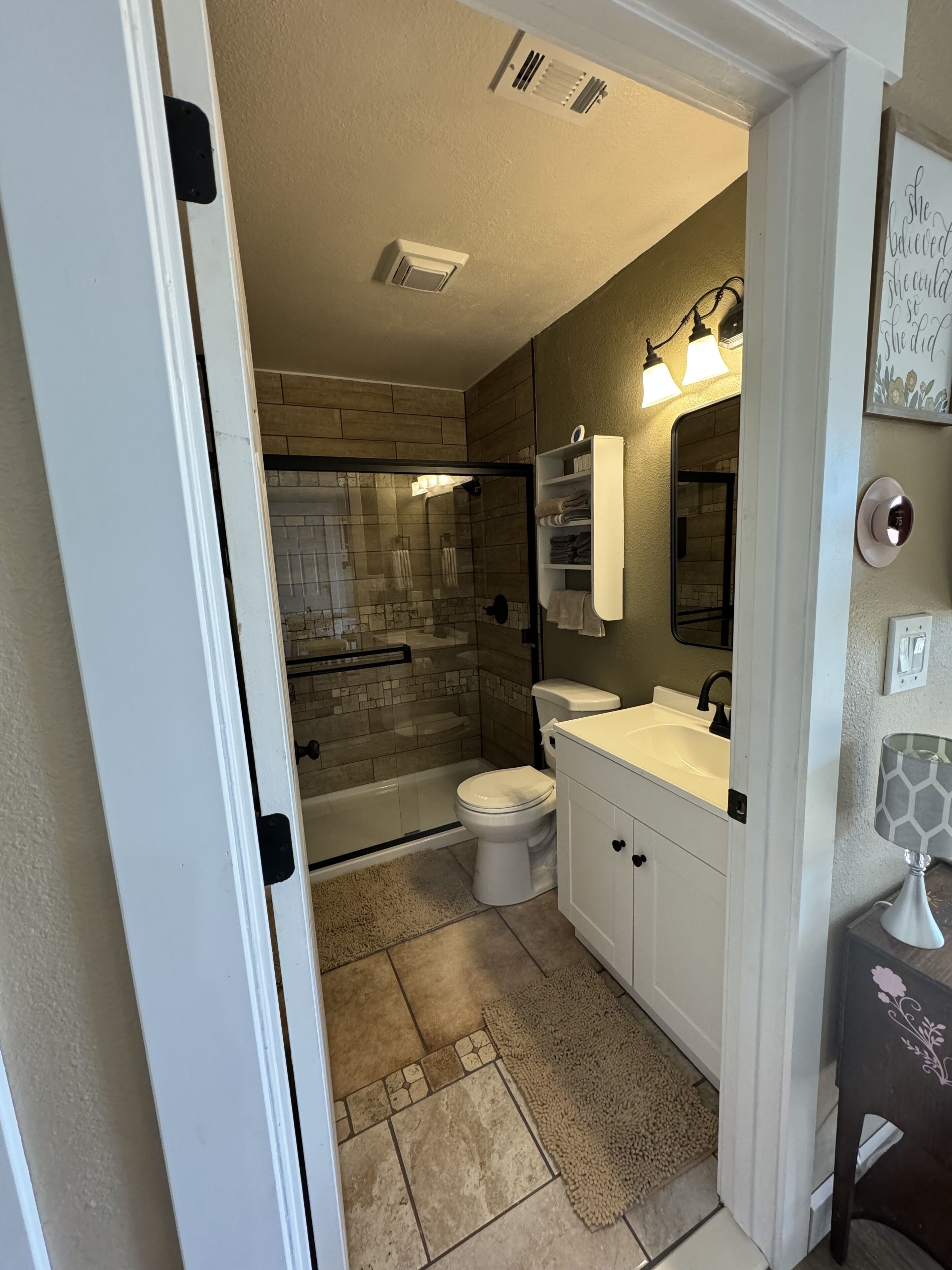 A modern bathroom with a glass-enclosed shower, a toilet, and a sink with a vanity.