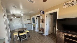 A spacious living area with a dining table, a TV, and a kitchen in the background. - Relax & Unwind in a Serene Retreat Near the Beach (Port Arthur)