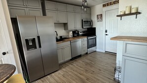 A modern kitchen with stainless steel appliances, wooden flooring, and light gray cabinets. - Relax & Unwind in a Serene Retreat Near the Beach (Port Arthur)
