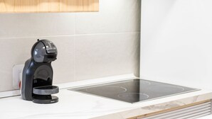 Una cocina moderna con una placa de inducción empotrada y una cafetera sobre la encimera.