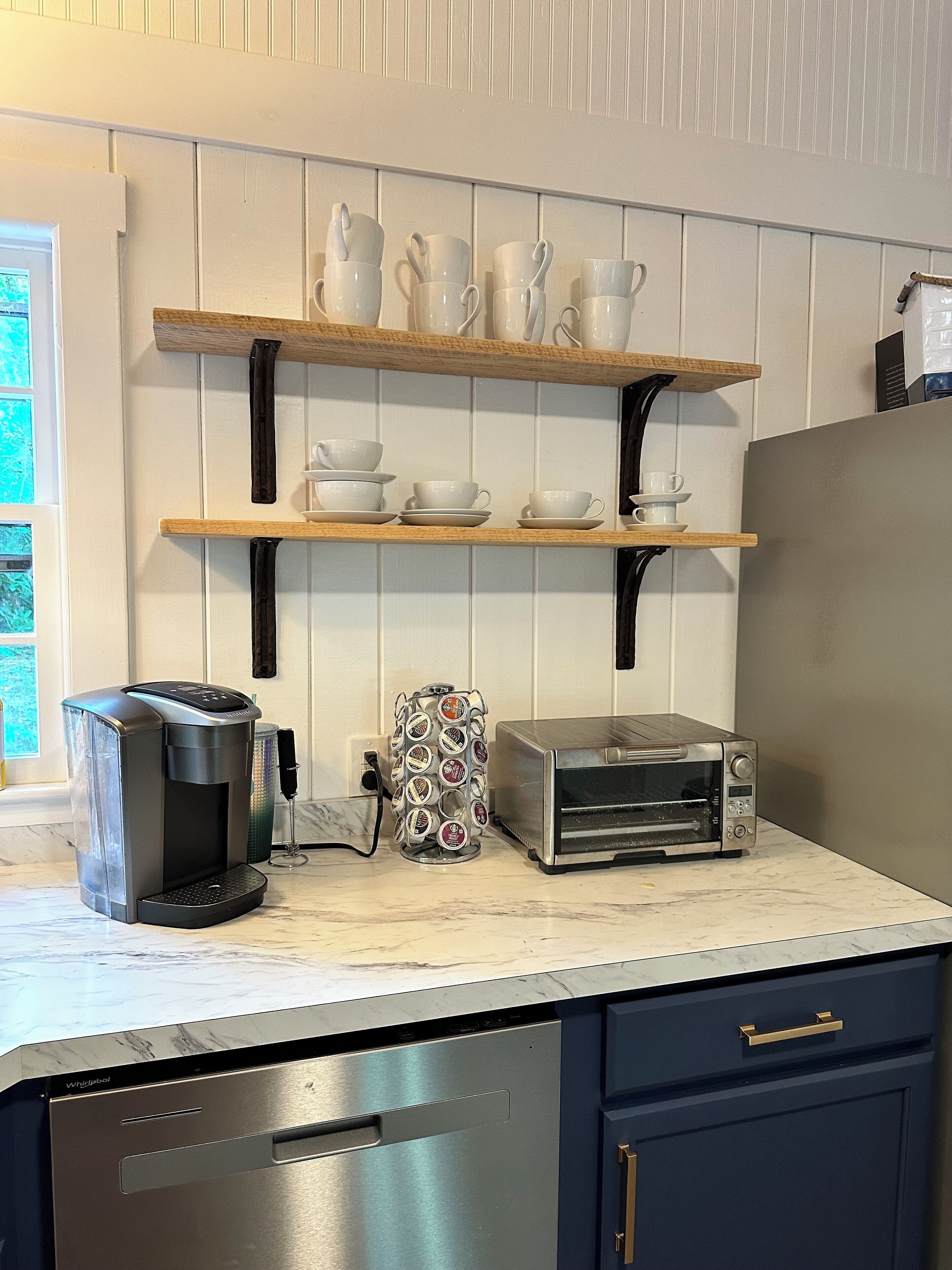 A kitchen with a coffee maker, toaster, and shelves with cups and bowls.