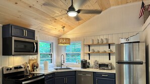 Una cocina moderna con armarios oscuros, electrodomésticos de acero inoxidable y techo de madera.