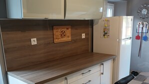 A kitchen with a wooden countertop, white cabinets, and a tiled floor.