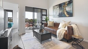 A modern living room with a brown leather sofa, a coffee table, and a large abstract painting on the wall. - Atlantic Port 9 (Cape Town)