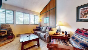 Una sala de estar acogedora con chimenea, un sofá, una mesita de centro y una lámpara.