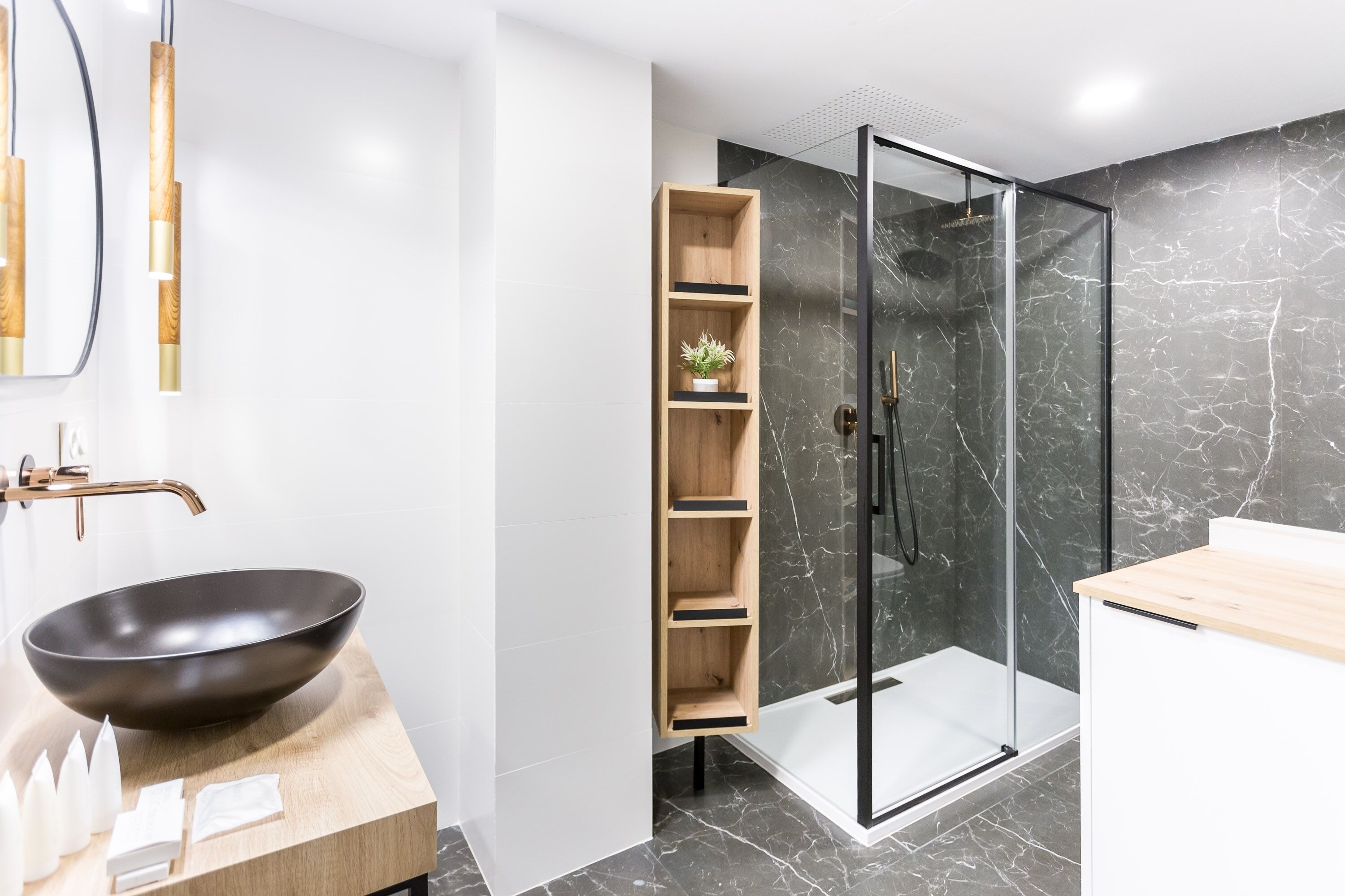 Ein modernes Badezimmer mit einem schwarzen Waschbecken, Holzregalen, einer Duschkabine aus Glas und Marmorböden.