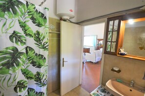 A bathroom with a sink, mirror, and shower curtain with a tropical leaf pattern. - La Rotta by Solturelba (Capoliveri)