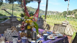A table set with various dishes, a coffee pot, and a vase with flowers, overlooking a scenic landscape. - La Rotta by Solturelba (Capoliveri)