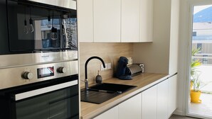 Una cocina moderna con electrodomésticos de acero inoxidable, un lavamanos negro y armarios blancos.