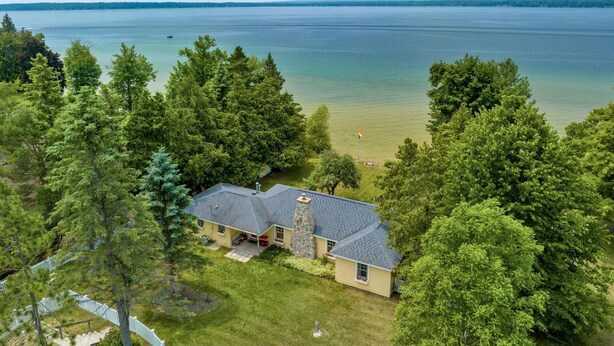 Ein Haus mit einem Steinkamin, einer Veranda und Blick auf einen See.