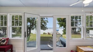Ein Zimmer mit einer großen Schiebeglasdoor, die auf eine Terrasse mit Blick auf das Wasser führt.
