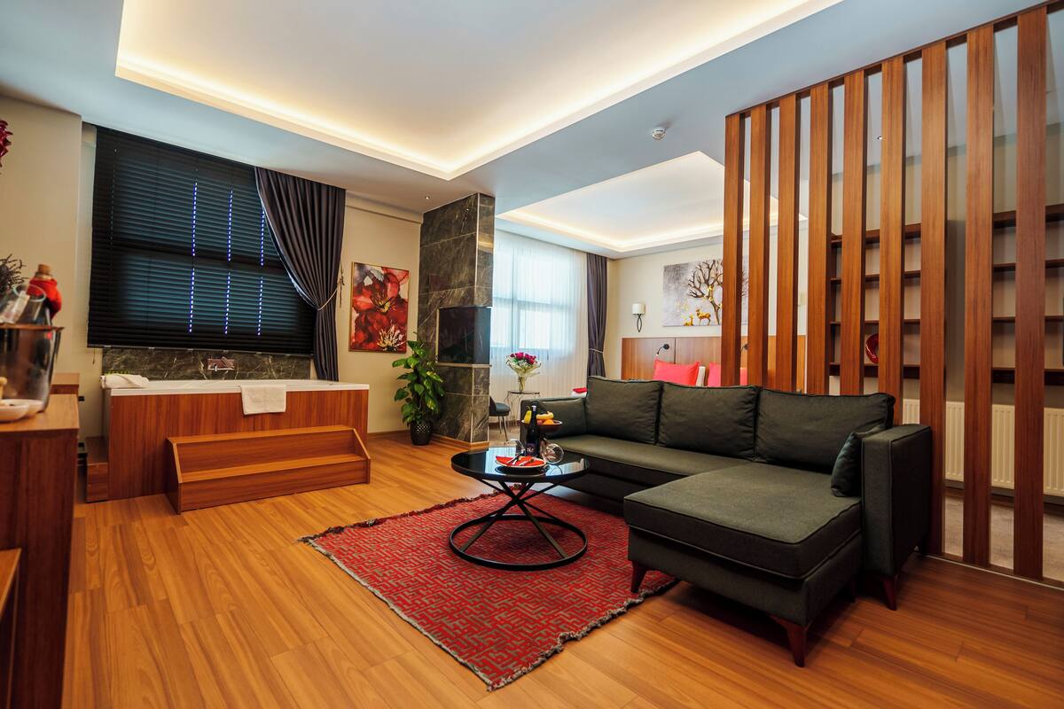 Uma sala de estar moderna com um sofá, uma mesa de centro, uma lareira e um separador de madeira.