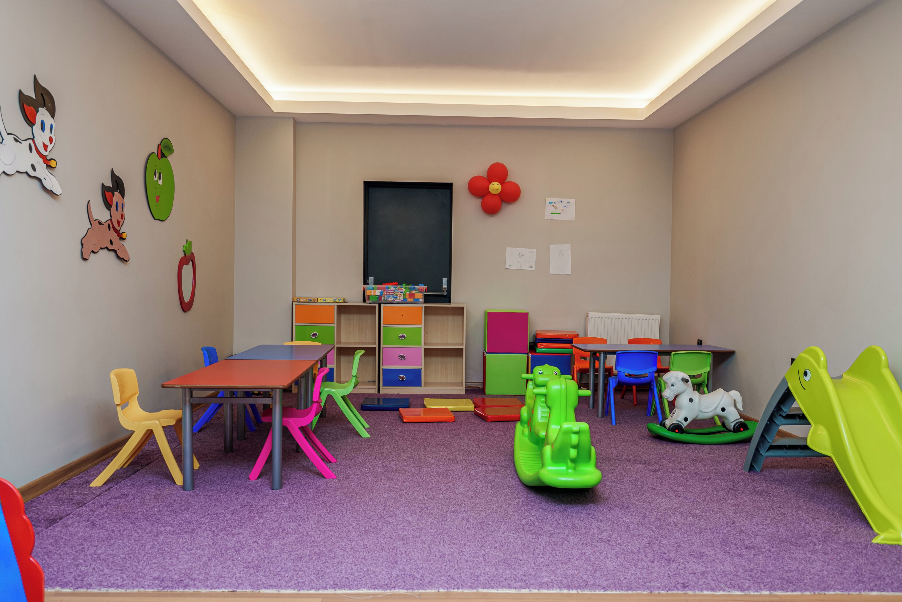 A children's playroom with colorful toys, a table, chairs, and a television.