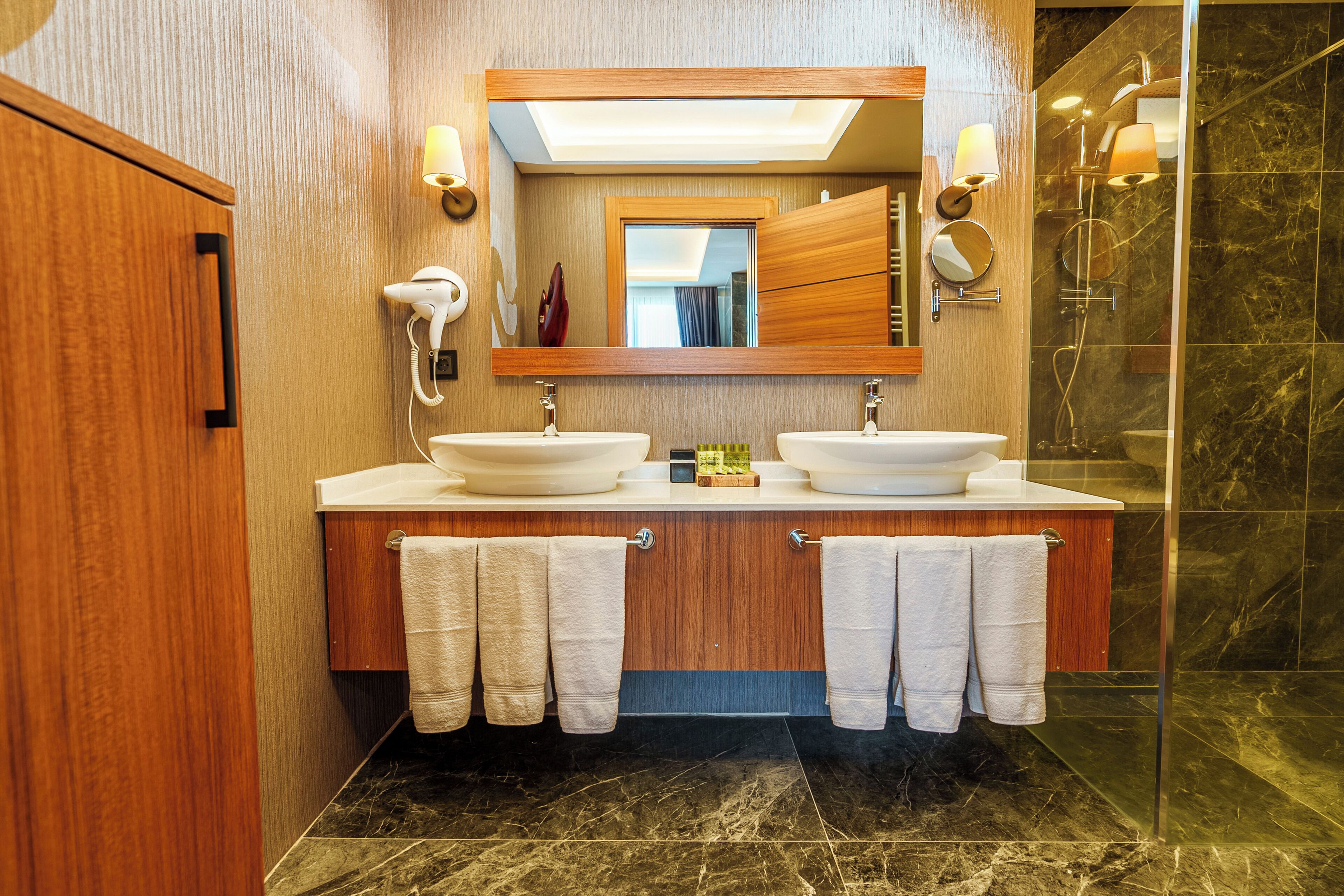 A modern bathroom with two sinks, a large mirror, and a glass shower enclosure.