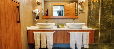 A modern bathroom with two sinks, a large mirror, and a glass shower enclosure.
