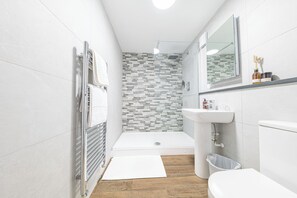 A modern bathroom with a shower, toilet, and sink.