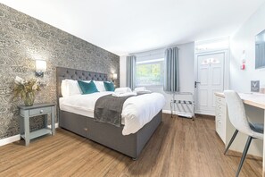 A modern bedroom with a large bed, a desk, and a chair.