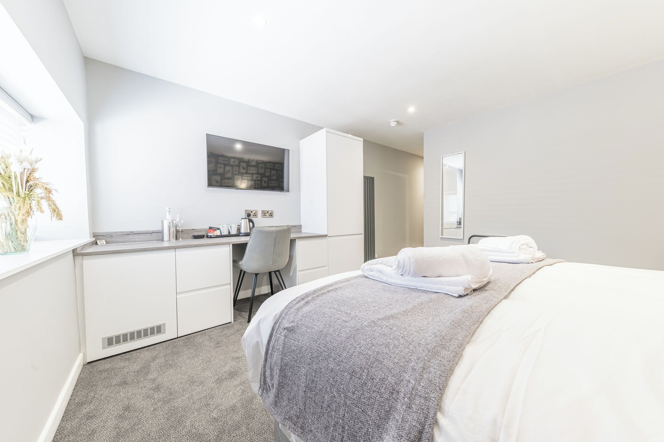 A modern hotel room with a bed, a desk, and a chair.