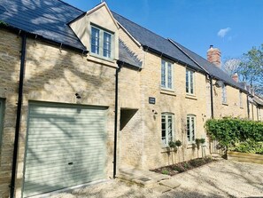 Traditional home with a gabled roof and ample parking, featuring large windows with shutters for added security.