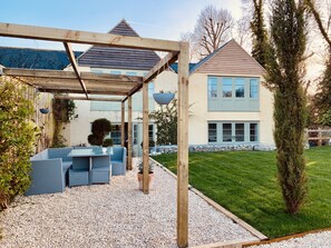 Relax in a serene outdoor seating area surrounded by lush greenery and a charming building.