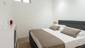 Une chambre à coucher avec un lit, une table de chevet et une fenêtre.