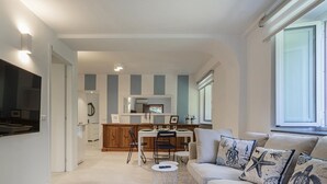 Eine moderne Küche mit Essbereich, einer Couch mit Zierkissen und einem großen Fenster.