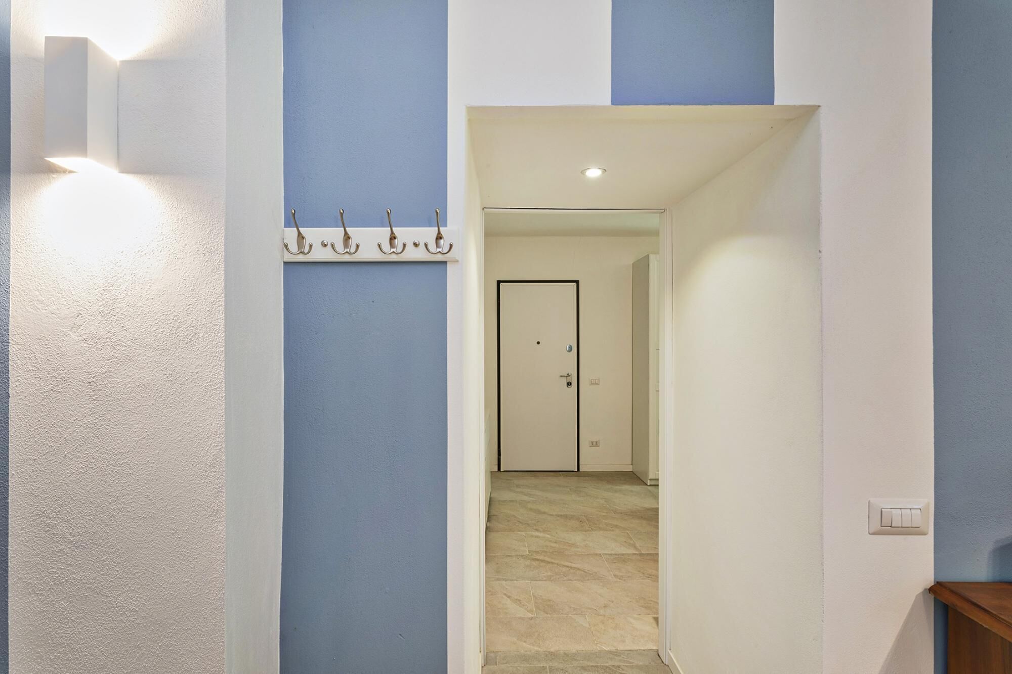 A hallway with a coat rack, a door, and a light fixture.