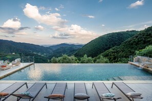 An infinity pool with lounge chairs and a scenic mountain view. - Villa Grema in Pescaglia (Pescaglia)