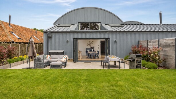 Een modern gebouw met een ruime open patio, een eethoek en een barbecueplaats.