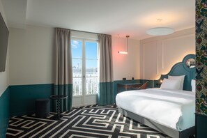 A hotel room with a bed, a desk, a chair, a window with curtains, and a patterned carpet. - LABE Hôtel Tours Centre Gare (Tours)